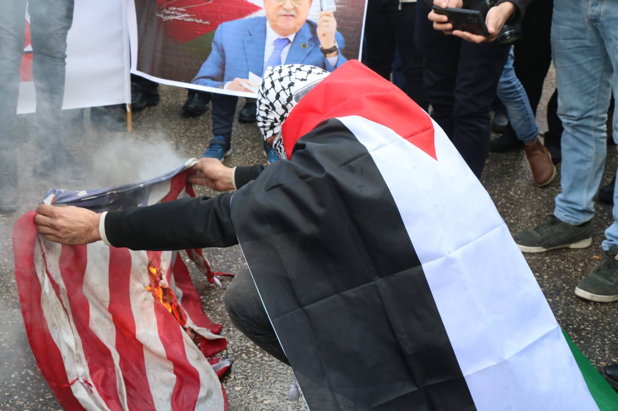 A Palestinian demonstrator burns the American flag in Bethlehem in protest of US President Donald Trump's peace plan. (Photo: Yumna Patel)
