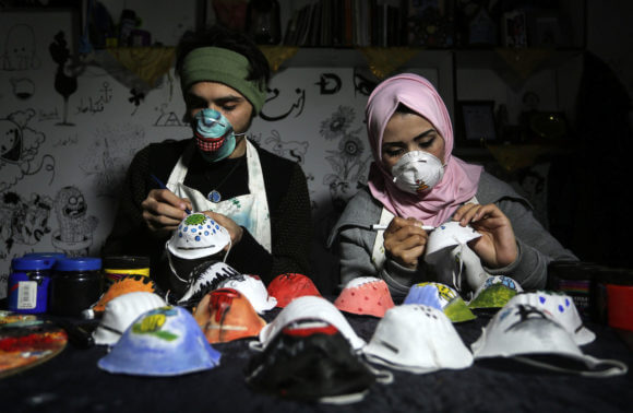 Palestinian artists Samah Said and Dorgham Krakeh paint N95 respirators for a project raising awareness about the coronavirus COVID-19, in Gaza City on March 25, 2020. (Photo: Ashraf Amra/APA Images)
