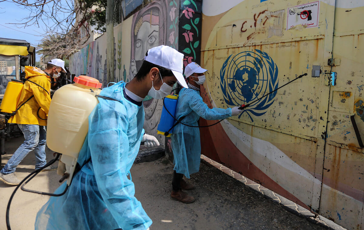 Palestinian workers spray disinfectant outside an UNRWA school as a preventive measure amid fears of the spread of the coronavirus, in Deir Al Balah in the Gaza Strip, on April 2, 2020. (Photo: Ashraf Amra/APA Images)