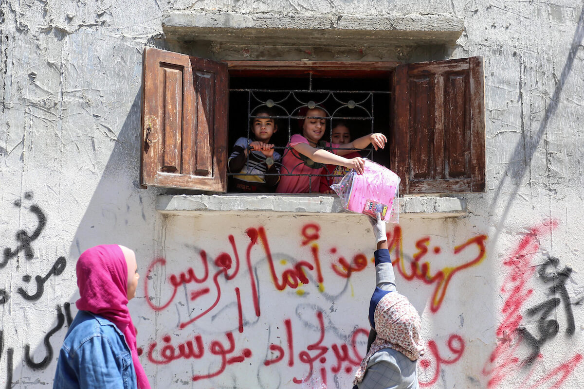 Palestinian activists and volunteers from the Women's Program Center distribute crafts and reading material to children confined at home due to the novel coronavirus pandemic, in the Deir al-Balah refugee camp in the Gaza Strip, on April 13, 2020. (Photo: Ashraf Amra)