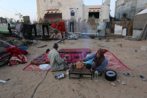 Members of a Palestinian family break their fast during the holy fasting month of Ramadan at the site of their destroyed house in Khan Youns southern in Gaza city on April 26, 2020. Photo by Ashraf Amra