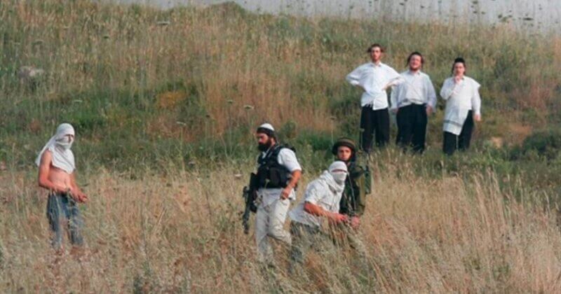 Armed and masked Israeli settlers harassing Palestinians. Published by IMEMC in April 2020, but photo is undated.