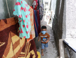 A Palestinian child wears a mask as he runs between alleys in Al-Shate' refugee camp, in the Gaza Strip on May 18, 2020. Photo by Mahmoud Al-Hindi/APA Images