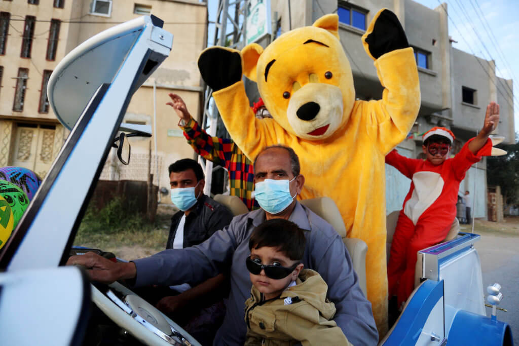Palestinian clowns drive from to the homes of children to entertain them during the Eid al-Fitr holiday which marks the end of the Muslim holy month of Ramadan, amid concern about the spread of the coronavirus disease in Khan Younis in the southern Gaza strip on May 26, 2020. (Photo: Ashraf Amra/APA Images)
