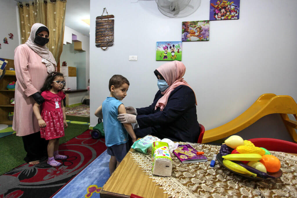 Palestinian Kindergarten teacher wearing a face mask and gloves, play with children after the decision to open schools across the Gaza Strip, in Gaza City, on June 2, 2020. (Photo: Mahmoud Ajjour/APA Images)
