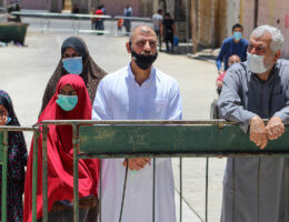 Israeli soldiers stands guard as Palestinians wearing face masks enter the Ibrahimi Mosque to perform Friday prayers in the midst of the coronavirus pandemic in the West Bank city of Hebron on June 26, 2020. (Photo: Mosab Shawer/APA Images)