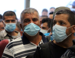 Palestinian laborers wearing masks queue to enter Israel through the Mitar checkpoint in the West Bank city of Hebron on June 28, 2020. (Photo: Mosab Shawer/APA Images)