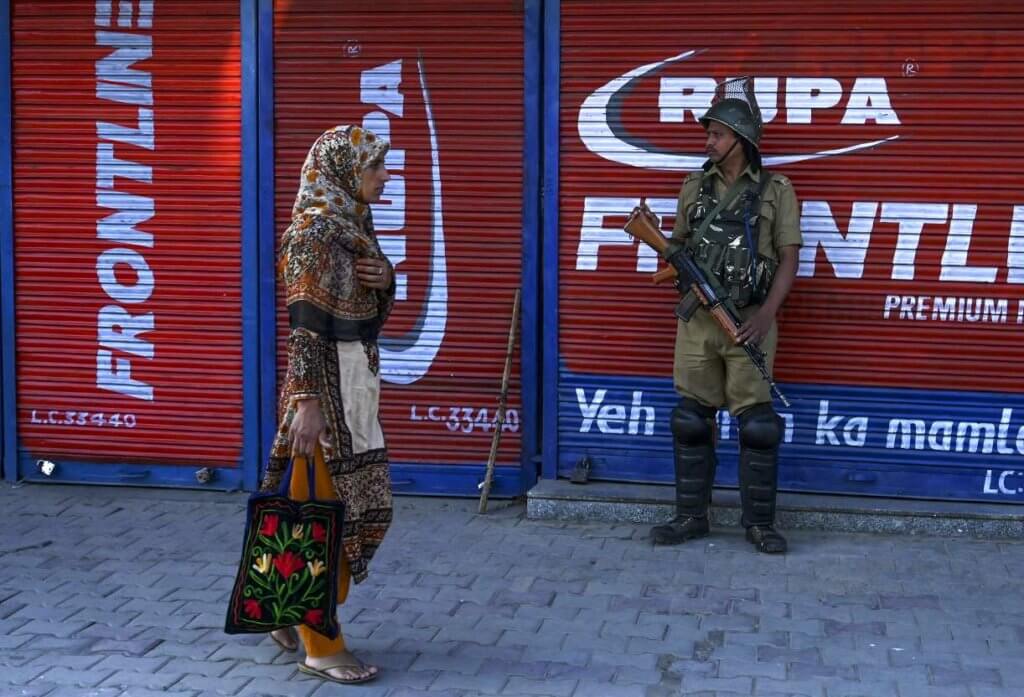 A security personnel stands guard as a Kashmiri woman walks past in front of closed shops in Srinagar on August 23, 2019. (Photo: Tauseef Mustafa/AFP/Getty Images)