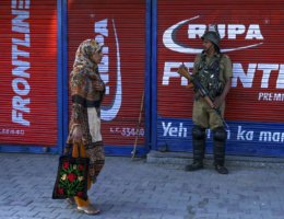A security personnel stands guard as a Kashmiri woman walks past in front of closed shops in Srinagar on August 23, 2019. (Photo: Tauseef Mustafa/AFP/Getty Images)