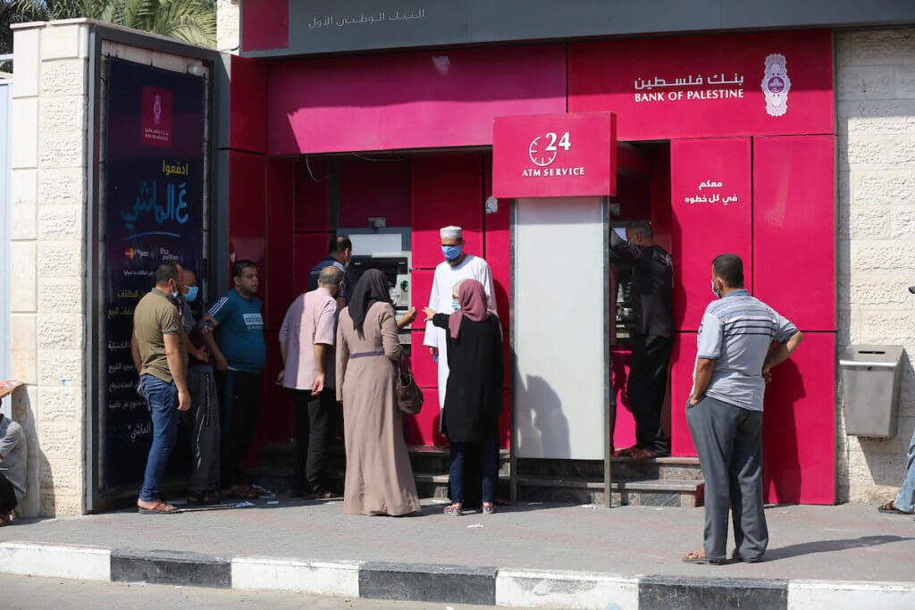 Palestinian Authority employees wear face masks as they wait to receive their salaries from a Palestine Bank ATM in the central Gaza Strip, September 1, 2020. (Photo: Ashraf Amra)