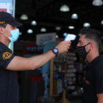 A Palestinian security guard takes the temperature of a visitor outside a mall in Gaza City on September 21, 2020. (Photo: Mahmoud Ajjour/APA Images)