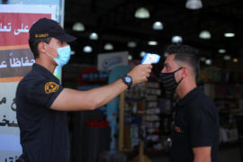 A Palestinian security guard takes the temperature of a visitor outside a mall in Gaza City on September 21, 2020. (Photo: Mahmoud Ajjour/APA Images)