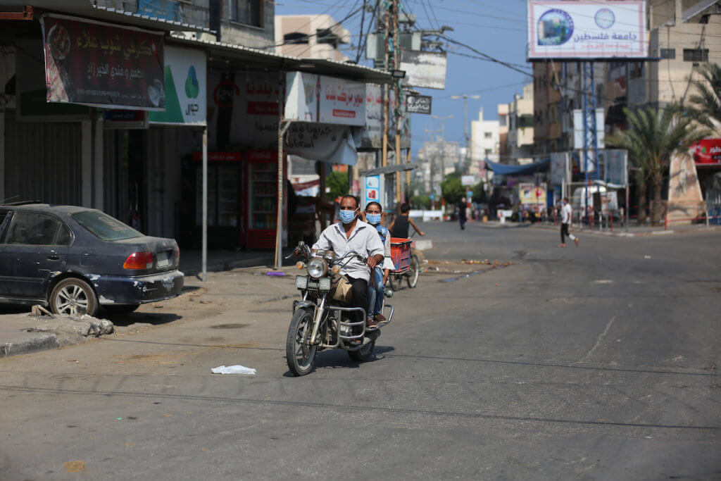 Palestinians riding a motorcycle wear face masks in a street during a lockdown imposed to mitigate the coronavirus outbreak in the Gaza Strip, in Deir al-Balah in the central Gaza Strip on August 30, 2020. (Photo: Ashraf Amra/APA Images)