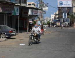 Palestinians riding a motorcycle wear face masks in a street during a lockdown imposed to mitigate the coronavirus outbreak in the Gaza Strip, in Deir al-Balah in the central Gaza Strip on August 30, 2020. (Photo: Ashraf Amra/APA Images)