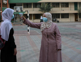A Palestinian student has her temperature taken by a school staff member as schools partially reopened amid the coronavirus pandemic, in Khan Younis in the southern Gaza Strip on October 10, 2020. (Photo: Ashraf Amra/APA Images)