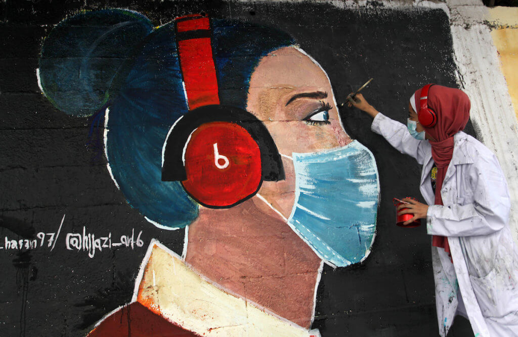 Palestinian artist paints a mural to raise awareness on wearing face masks amid the coronavirus pandemic in Gaza City on October 22, 2020. (Photo: Mahmoud Ajjour/APA Images)