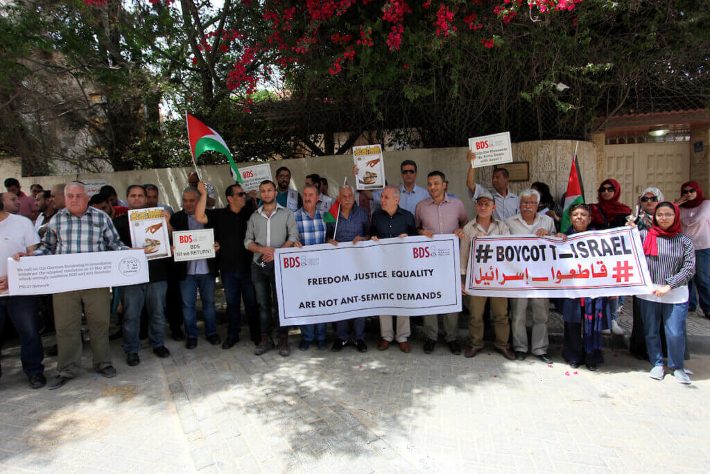 Palestinians hold banners during a protest against the decision of the German parliament against the boycott movement BDS outside Germany's Representative Office in Gaza City,on May 23, 2019. Germany's parliament condemned boycotts against as anti-Semitic on May 17, 2019, warning that its actions were reminiscent of the Nazis' campaign against Jews. (Photo: Mahmoud Ajjour/APA Images)