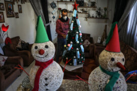 Palestinian artist Wissam Farhat decorates a Christmas tree with face masks amid the pandemic in Gaza City on December 20, 2020. (Photo: Mahmoud Ajjour/APA Images)