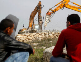 File Photo: Palestinian men watch the demolition of a Palestinian house at the order of the Israeli army in the West Bank village of Beit Ula, west of Hebron January 21, 2016. The owners of the house said they were informed by the Israeli army that the demolition was carried out because they did not have an Israeli-issued construction permit. (Photo: Wisam Hashlamoun/APA Images)