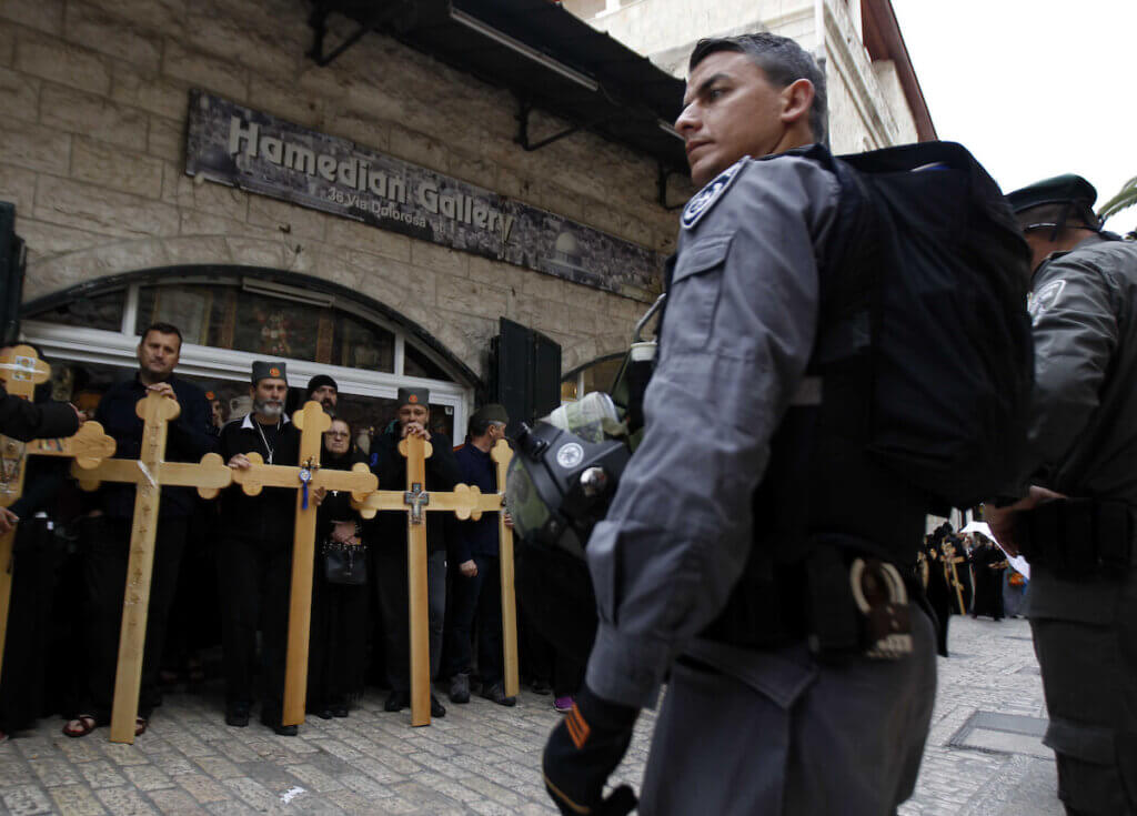 Israeli policemen stand in front of Orthodox Christians at the Via Dolorosa near the Church of the Holy Sepulchre during the Good Friday processions retracing the route Christian believe was taken by Jesus to his crucifixion, in Jerusalem's Old City on April 10, 2015. (Photo: Saeb Awad/APA Images)