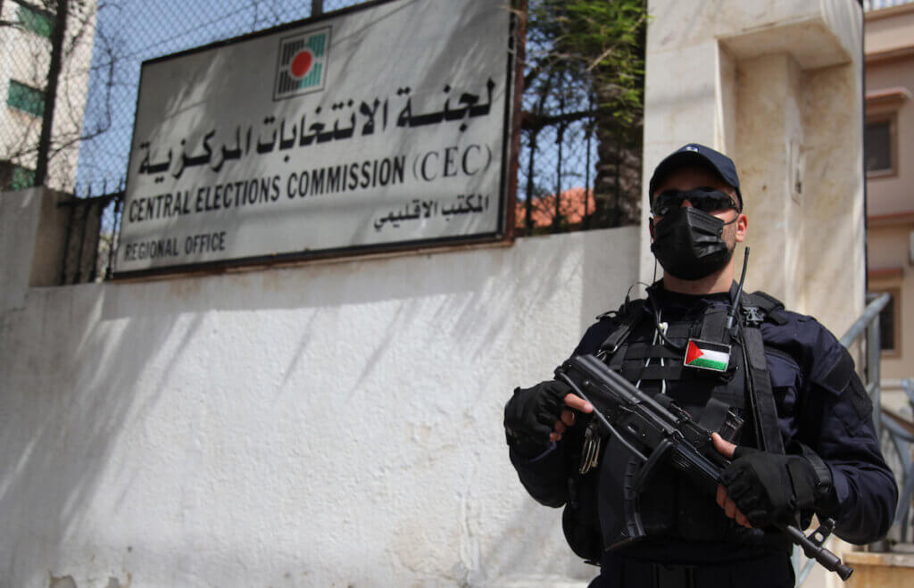 Policemen stand guard as Palestinians begin registering party lists for May parliamentary election, at the Central Elections Commission's office in Gaza City on March 20, 2021. (Photo: Mahmoud Ajjour/APA Images)