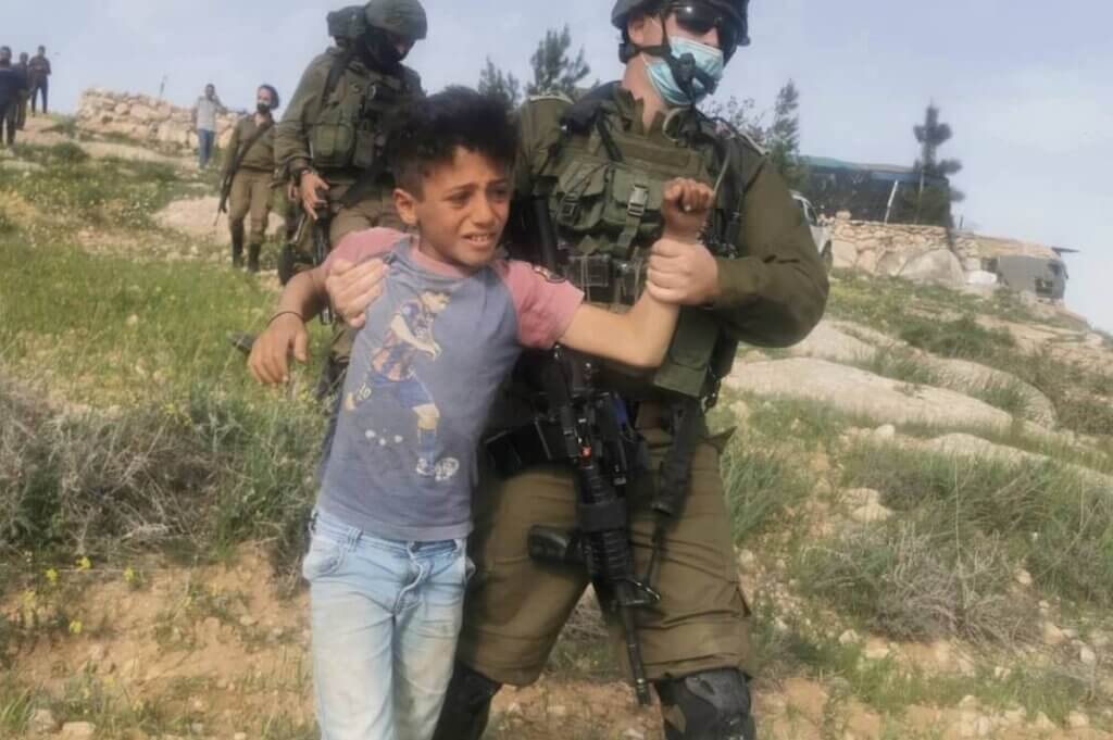 An Israeli soldier detains a Palestinian boy in the Masafer Yatta area on March 10th, 2021. (Photo: B'Tselem)