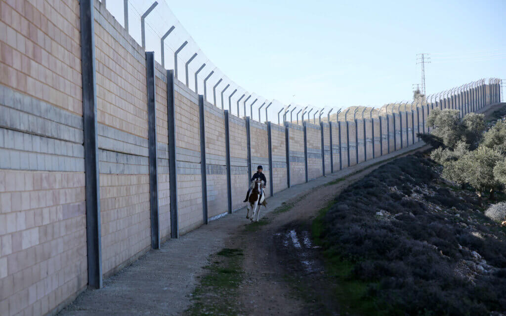 A Palestinian boy rides a horse near the separation wall during an equestrian training at the Palestinian Equestrian Club, in Rafat near Jerusalem on February 3, 2019. Photo: Shadi Jarar'ah/APA Images.