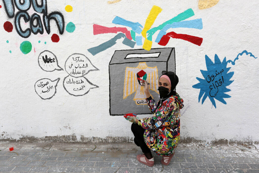 Palestinian artists Dana Jhish, 19, adds the final touches to a mural painting calling on people to vote during the upcoming elections (legislative in May and presidential in July), on a street in Gaza City, on March 24, 2021. (Photo: Photo by Ashraf Amra/APA Images)
