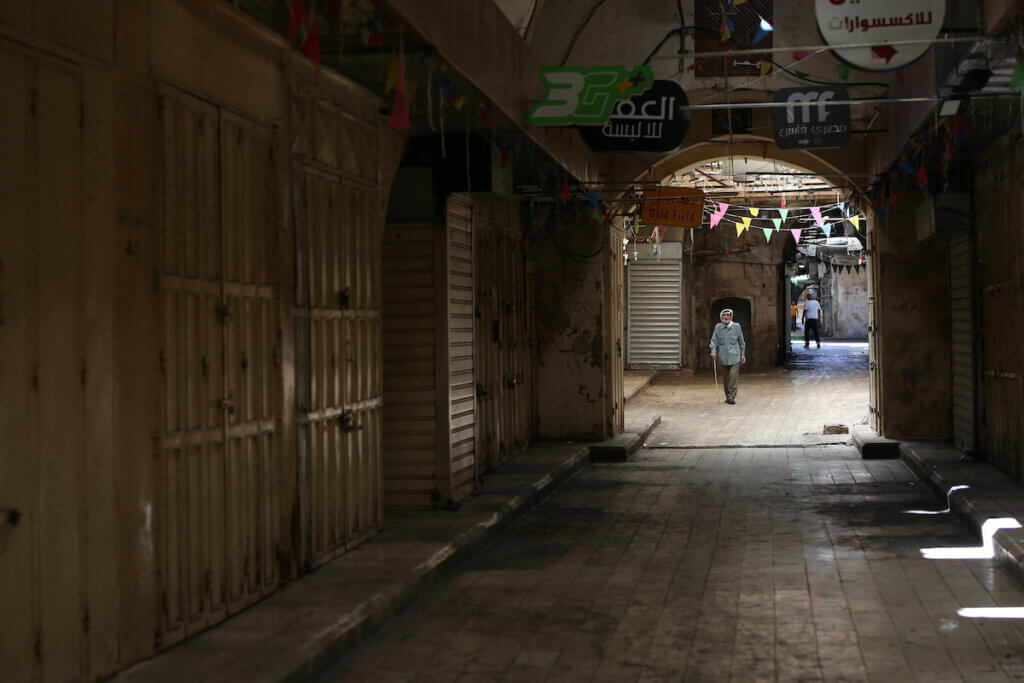 A Palestinian man walks past shuttered stores in the West Bank city of Nablus, as a general strike is observed in the occupied West Bank and Israeli cities in solidarity with Gaza and Jerusalem, on May 18, 2021. (Photo: Shadi Jarar'ah/APA Images)