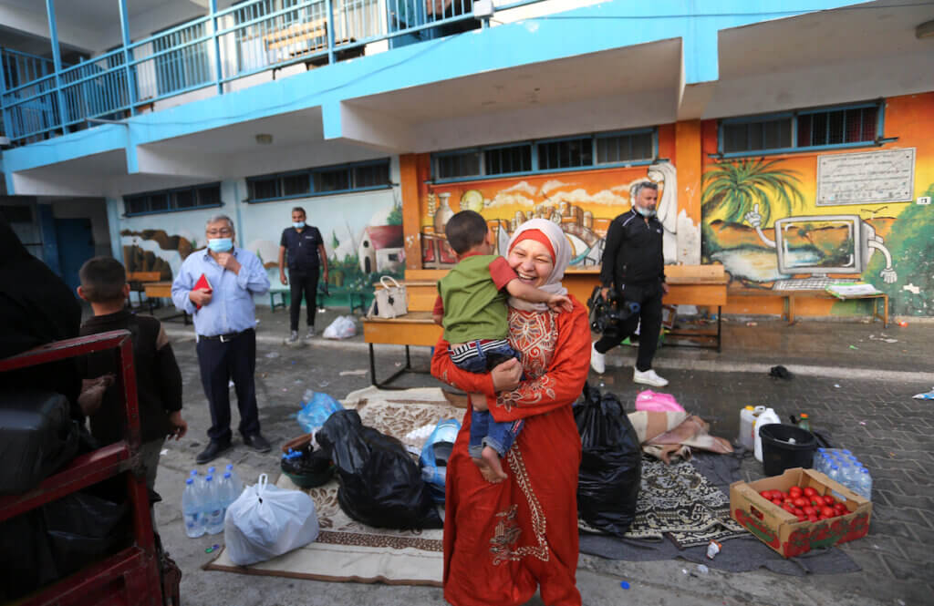 Palestinians who had taken shelter in a school run by The United Nations Relief and Works Agency for Palestine Refugees (UNRWA) transport their belongings as they return to their neighbourhoods hit by Israeli bombardment in Gaza City, after a ceasefire brokered by Egypt between Israel and Hamas, on May 21, 2021. (Photo: Ashraf Amra/APA Images)