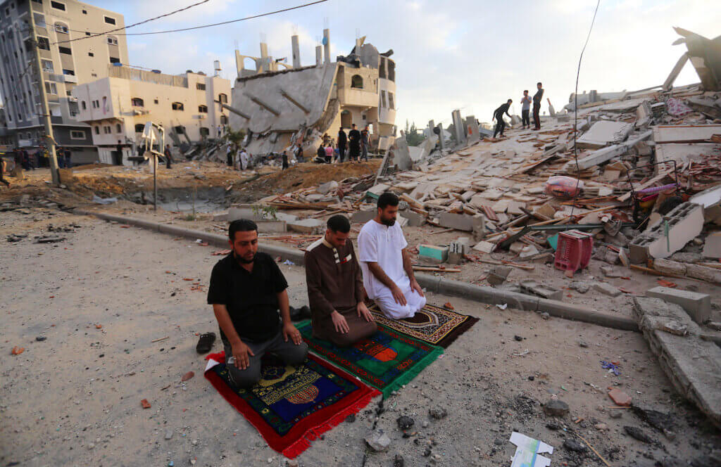 Palestinian Muslim men perform the morning Eid Al-Fitr prayer amid the destruction from Israeli attacks on the first day of the Muslim holiday which marks the end of the holy fasting month of Ramadan, in the northern Gaza Strip town of Beit Lahia, on May 13, 2021. (Photo: Ashraf Amra)