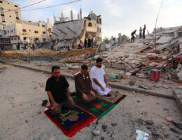 Palestinian Muslim men perform the morning Eid Al-Fitr prayer amid the destruction from Israeli attacks on the first day of the Muslim holiday which marks the end of the holy fasting month of Ramadan, in the northern Gaza Strip town of Beit Lahia, on May 13, 2021. (Photo: Ashraf Amra)