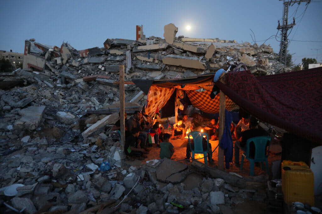 Palestinians sit in a tent that has been set up on top of the ruins of a building destroyed in recent Israeli air strikes, in Beit Lahia in the northern of Gaza Strip, on May 25. 2021. (Photo: Ashraf Amra/APA Images)