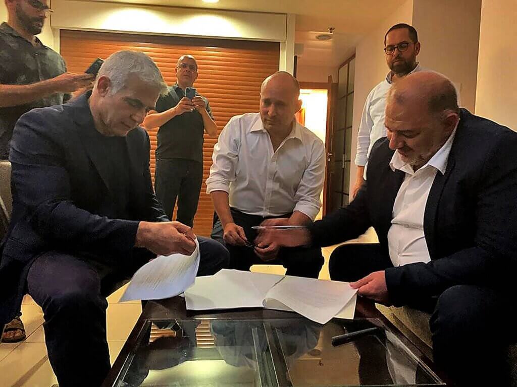 A handout picture provided by the United Arab List Raam on June 2, 2021, shows head of the Arab Israeli Islamic conservative party Raam Mansour Abbas (R) signing a coalition agreement with Israel's opposition leader Yair Lapid (L) and right-wing nationalist tech millionaire Naftali Bennett in Ramat Gan near the coastal city of Tel Aviv. - Israel's opposition leader Yair Lapid said he had succeeded in forming a coalition to end the rule of Prime Minister Benjamin Netanyahu, the country's longest serving leader. (Photo: United Arab List Raam/AFP via Getty Images)