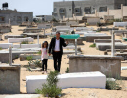 Riad Ishkontana, 42, and his daughter Suzy, 7, visit the graves of their family on the second day of Eid al-Adha in Gaza City on July 21, 2021. Suzy's mother, her two brothers and two sisters -- ages 2 to 9 -- were killed in a May 16 Israeli attack on the densely packed al-Wahda Street in Gaza City during the recent conflict between Israel and Hamas. (Photo: Ashraf Amra/APA Images)