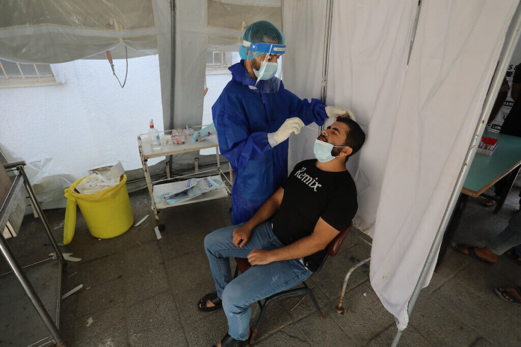 A Palestinian health worker collects a swab sample for a COVID-19 test at a temporary vaccination center set in Deir al-Balah in the Gaza Strip on August 26, 2021. (Photo: Ashraf Amra/APA Images)