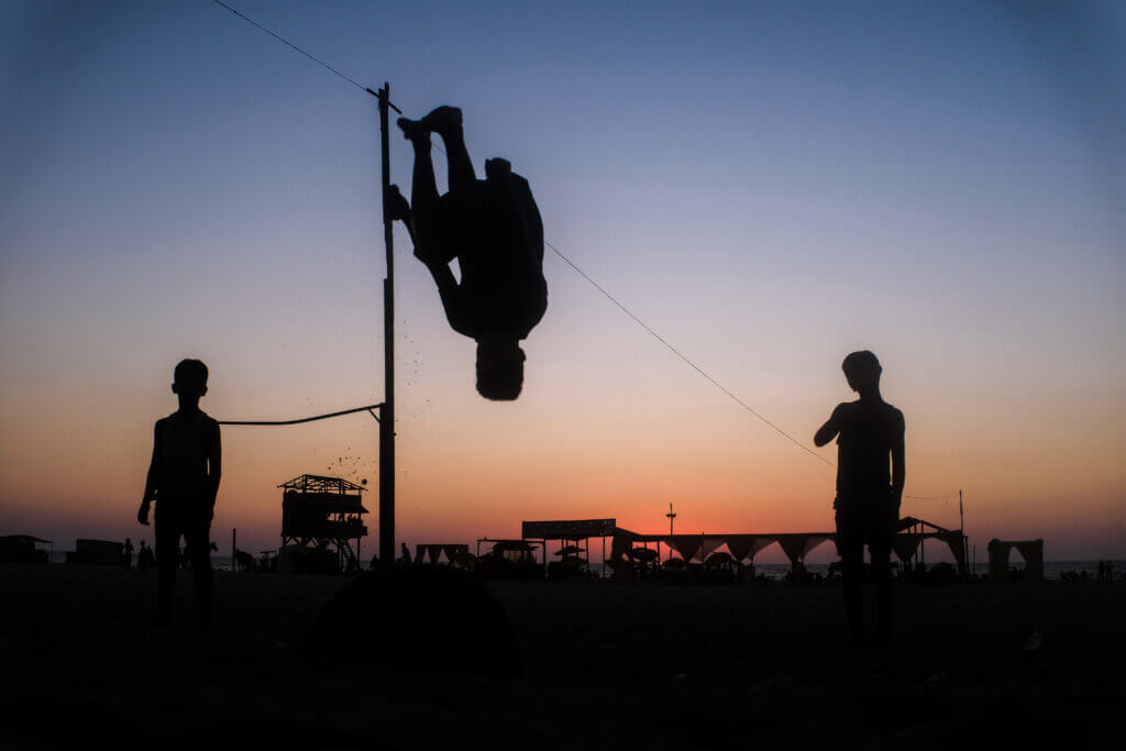 Three brothers display their acrobatic abilities on a beach in western Gaza on August 11, 2021. (Photo: Mahmoud Nasser)