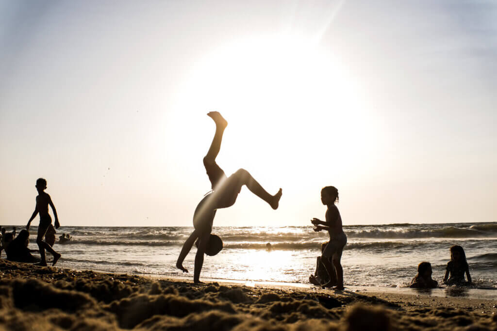 Palestinian child displays his acrobatic skills in front of beach goers near central Gaza on August 12, 2021. (Photo: Mahmoud Nasser)