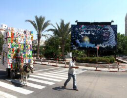 A Palestinian boy rides his donkey cart past a billboard which bears a portait of late Palestinian leader Yasser Arafat, with the Arabic slogan: "My dream will not be compete without Jerusalem," in central Gaza City on September 17, 2011. (Photo: Ashraf Amra/APA Images)