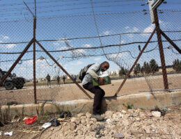 A Palestinian labourer crosses through a hole in a security fence in the West Bank town of Jenin, on September 6, 2021. (Photo: APA Images)