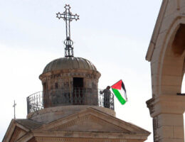 A Palestinian Christian man waves the Palestinian flag on the Church of the Nativity in the West Bank city of Bethlehem on January 25, 2015. (Photo: Muhesen Amren/APA Images)