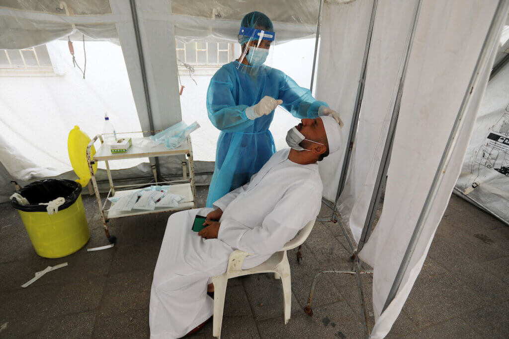 A Palestinian health worker collects a swab sample from a person for a COVID-19 test at a temporary vaccination center set up, in Deir al-Balah in the center of the Gaza Strip on September 28, 2021.