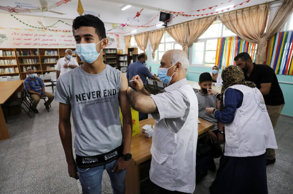 Palestinian high school students get inoculated with a dose of the Covishield vaccine at a school in Nuseirat refugee camp in the central Gaza Strip on September 1, 2021. (Photo: Ashraf Amrac/APA Images)