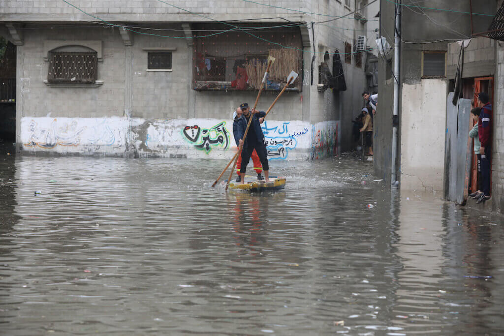 Palestinian civil defense volunteers ride a boat across flood waters in Jabalia refugee camp in the northern Gaza Strip following rain storms, on January 16, 2022. (Photo: Ashraf Amra/APA Images)