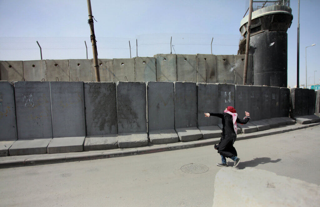 Qalandiya checkpoint. A Palestinian woman throws stones at Israeli border policemen during a rally ahead of International Woman's Day, at Qalandiya checkpoint near the West Bank city of Ramallah March 7, 2015. Photo by Shadi Hatem (c) APA Images