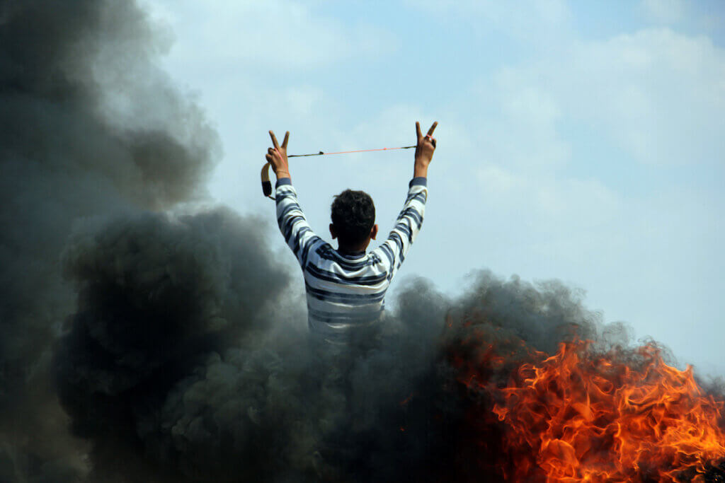 Un giovane palestinese mostra il segno della vittoria durante gli scontri con le forze di sicurezza israeliane vicino al confine con Israele, a est del campo profughi di Jabalia, nel nord della Striscia di Gaza, il 21 maggio 2014.  (Foto: Khaled al-Sabbah/APA Images)