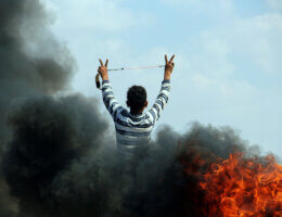 A Palestinian youth flashes the victory sign during clashes with Israeli security forces near the border with Israel, east of Jabalia refugee camp in northern Gaza Strip, May 21, 2014 . (Photo: Khaled al-Sabbah/APA Images)