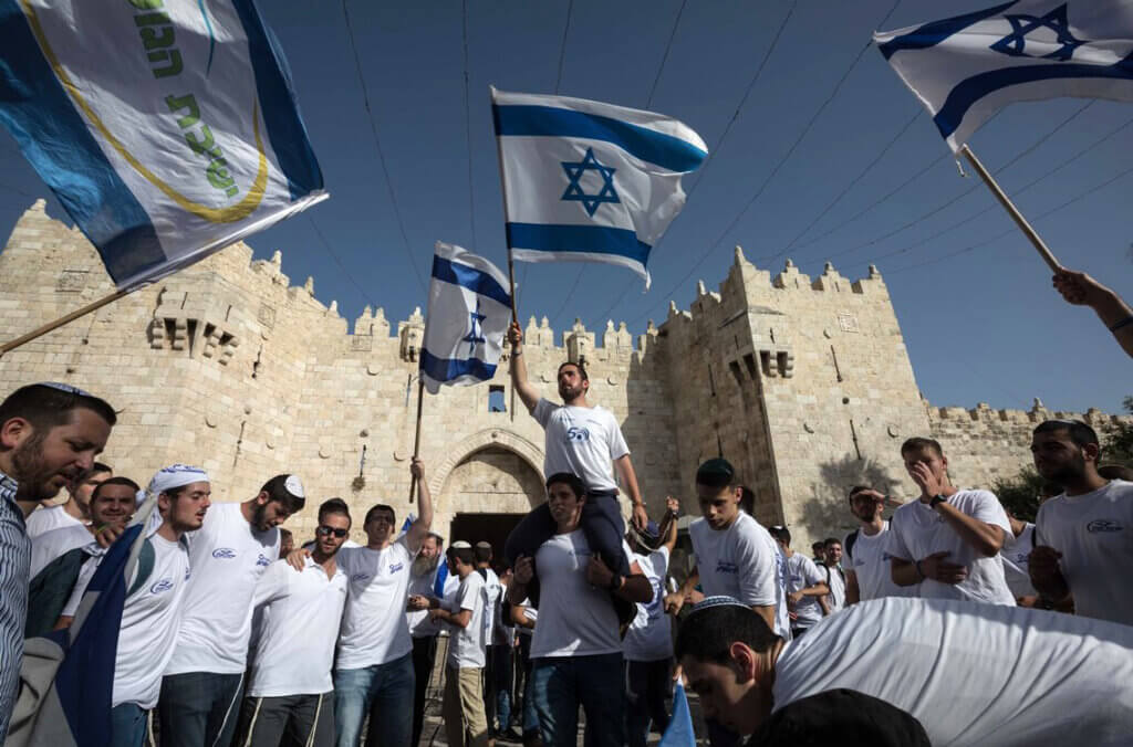 Settlers wave Israeli flags as they enter Damascus Gate as part of a nationalistic flag march in Jerusalem's Old City, June 2, 2019. (Photo: Afif Amera/WAFA)