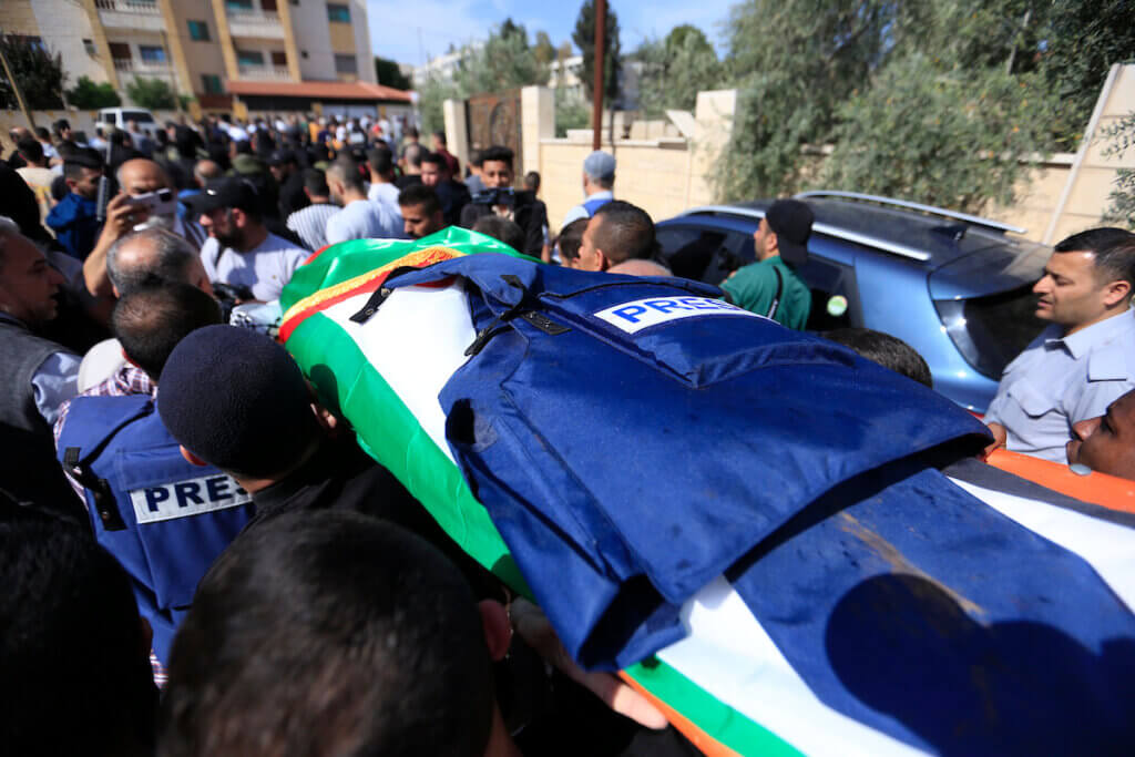 Mourners carry the body of Al Jazeera reporter Shireen Abu Akleh, with her press flak jacket covering her casket, during her funeral in the West Bank city of Jenin on May 11, 2022. (Photo: Shadi Jarar'ah/APA Images)