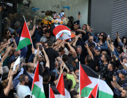 Palestinians carry the flag-draped body of veteran Al-Jazeera journalist Shireen Abu Akleh as it is carried toward the offices of the news channel in the West Bank city of Ramallah, on May 11, 2022. (Photo: Wajed Nobani/APA Images)